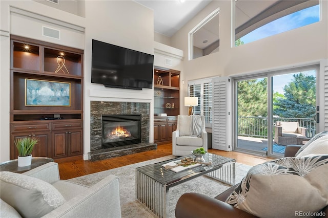 11 Canon Pl, Greenwood Village, CO 80111 - living area featuring wood finished floors, a towering ceiling, a stone fireplace, and built in shelves