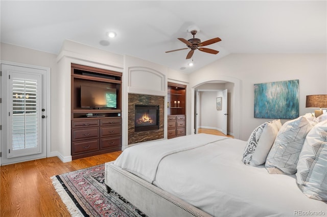 11 Canon Pl, Greenwood Village, CO 80111 - bedroom featuring vaulted ceiling, light wood-style flooring, a ceiling fan, arched walkways, and a glass covered fireplace