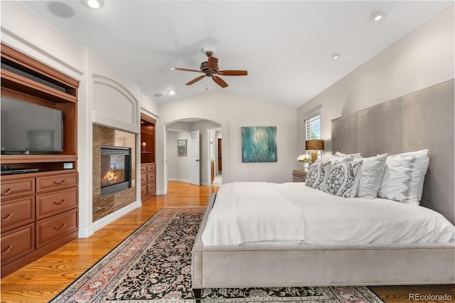 11 Canon Pl, Greenwood Village, CO 80111 - bedroom featuring arched walkways, light wood-type flooring, vaulted ceiling, a fireplace, and recessed lighting