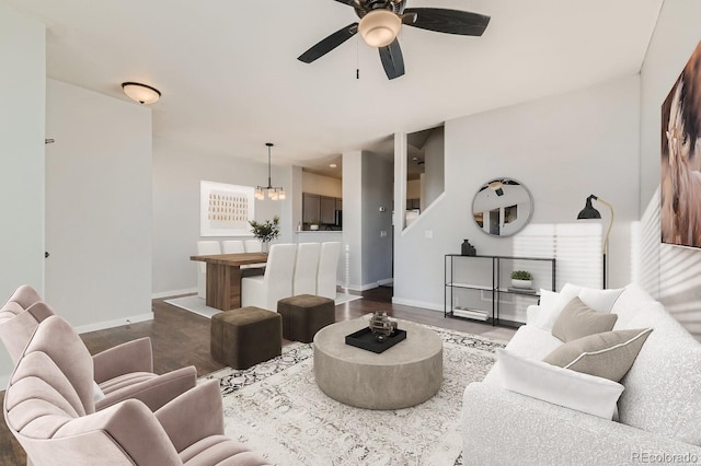 living room with ceiling fan with notable chandelier and dark hardwood / wood-style flooring