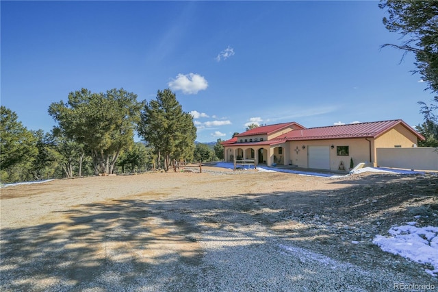 view of front of property with a garage, fence, metal roof, and stucco siding