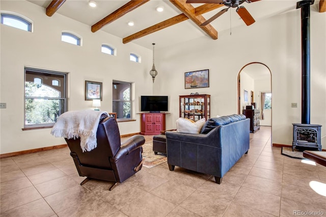 living area with a wood stove, a high ceiling, beam ceiling, and a wealth of natural light