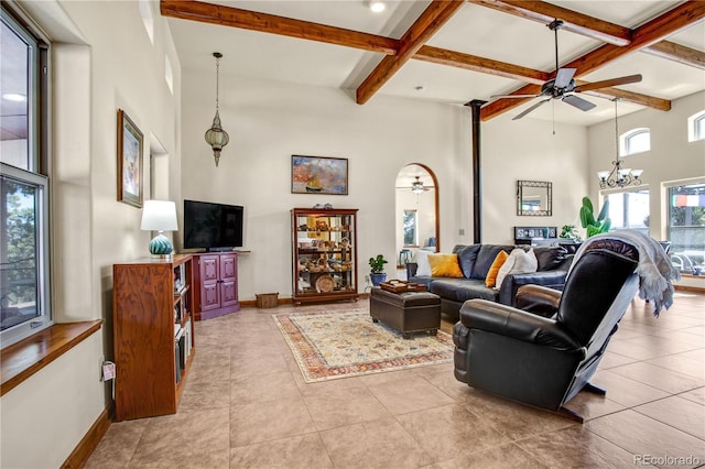 living room with a high ceiling, baseboards, beam ceiling, and ceiling fan with notable chandelier