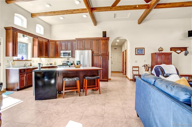 kitchen with arched walkways, a center island, light countertops, appliances with stainless steel finishes, and open floor plan