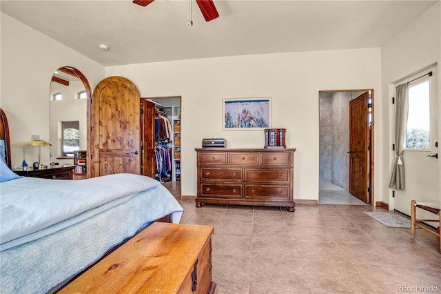 bedroom featuring a ceiling fan, a walk in closet, a closet, and light tile patterned flooring