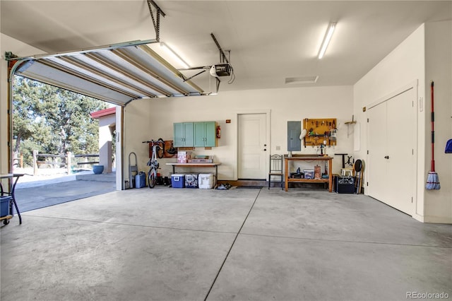 garage with a garage door opener, electric panel, and a workshop area