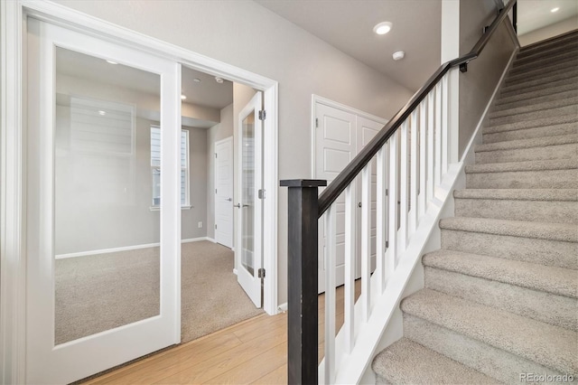 staircase featuring baseboards, wood finished floors, and recessed lighting