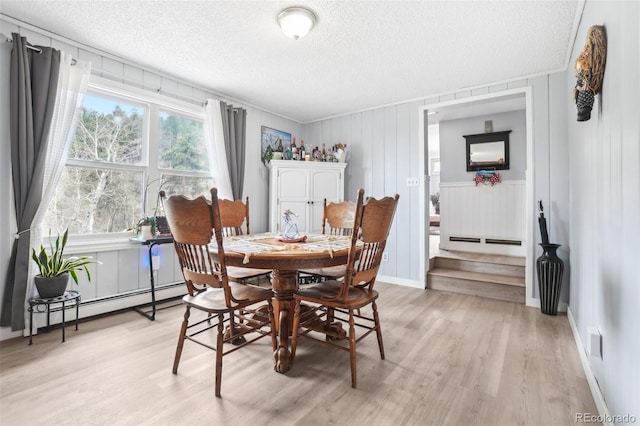 11827 Brook Rd, Golden, CO 80403 - dining space featuring a textured ceiling, light wood-style flooring, and a baseboard radiator