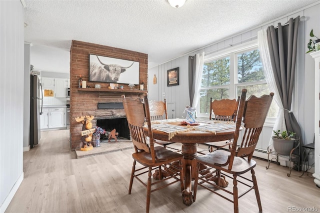 11827 Brook Rd, Golden, CO 80403 - dining area with a fireplace, light wood-style floors, a textured ceiling, and baseboards