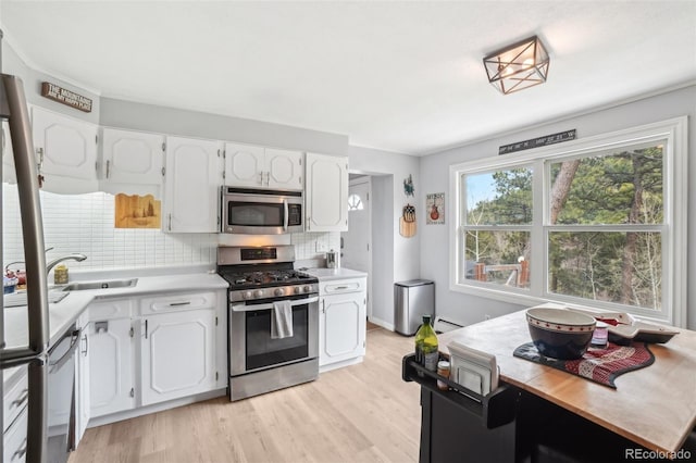 11827 Brook Rd, Golden, CO 80403 - kitchen featuring stainless steel appliances, a sink, white cabinetry, tasteful backsplash, and a baseboard radiator