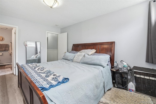 11827 Brook Rd, Golden, CO 80403 - bedroom featuring light wood-style floors, a baseboard radiator, and a textured ceiling