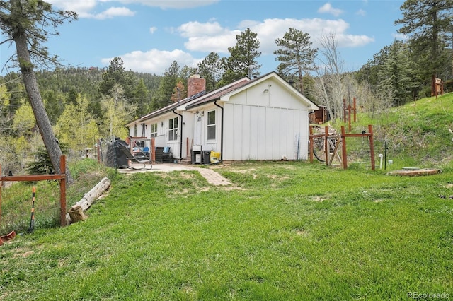 11827 Brook Rd, Golden, CO 80403 - view of home's exterior with board and batten siding, a chimney, a yard, and a patio area