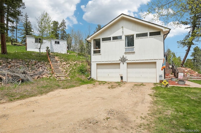 11827 Brook Rd, Golden, CO 80403 - view of front of home featuring dirt driveway, board and batten siding, stairway, and a garage