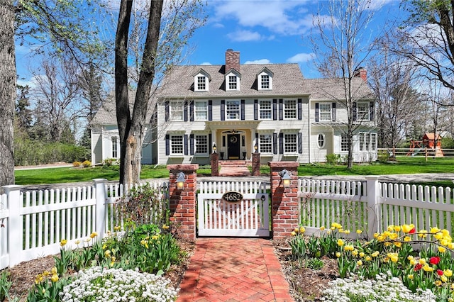 colonial-style house with a fenced front yard, a chimney, and a gate