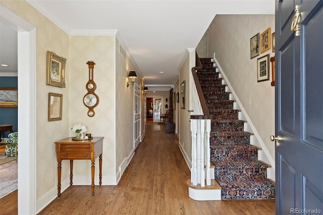 entryway featuring wood finished floors, stairs, ornamental molding, and baseboards
