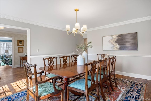 dining space featuring a chandelier, crown molding, wood finished floors, and baseboards