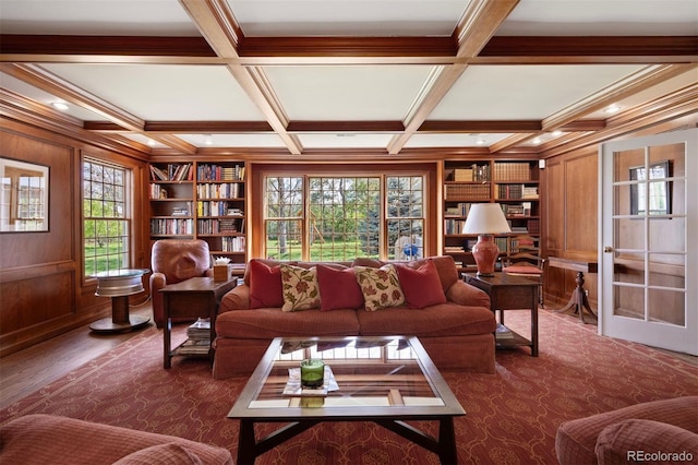 living room featuring beam ceiling, coffered ceiling, built in features, crown molding, and wooden walls
