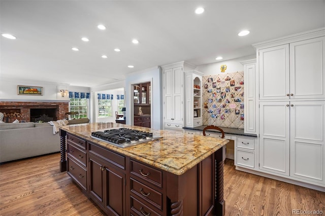 kitchen with stainless steel gas cooktop, white cabinets, light wood-type flooring, recessed lighting, and light stone counters