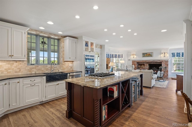kitchen with a sink, recessed lighting, stainless steel appliances, a center island, and white cabinetry
