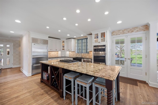 kitchen featuring appliances with stainless steel finishes, french doors, a kitchen island, open shelves, and white cabinetry