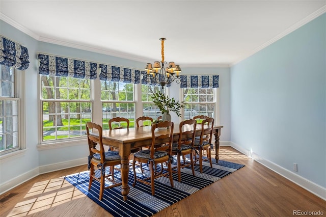 dining room with healthy amount of natural light, baseboards, a chandelier, and crown molding