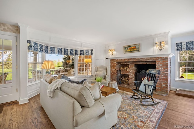 living room featuring wood finished floors, a fireplace, ornamental molding, and baseboards