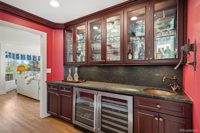 indoor wet bar featuring wine cooler, tasteful backsplash, light wood-style flooring, and crown molding