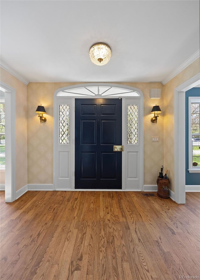 foyer featuring baseboards, wood finished floors, and ornamental molding