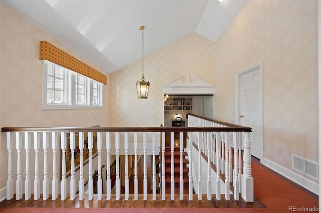 stairs featuring vaulted ceiling, wallpapered walls, and baseboards
