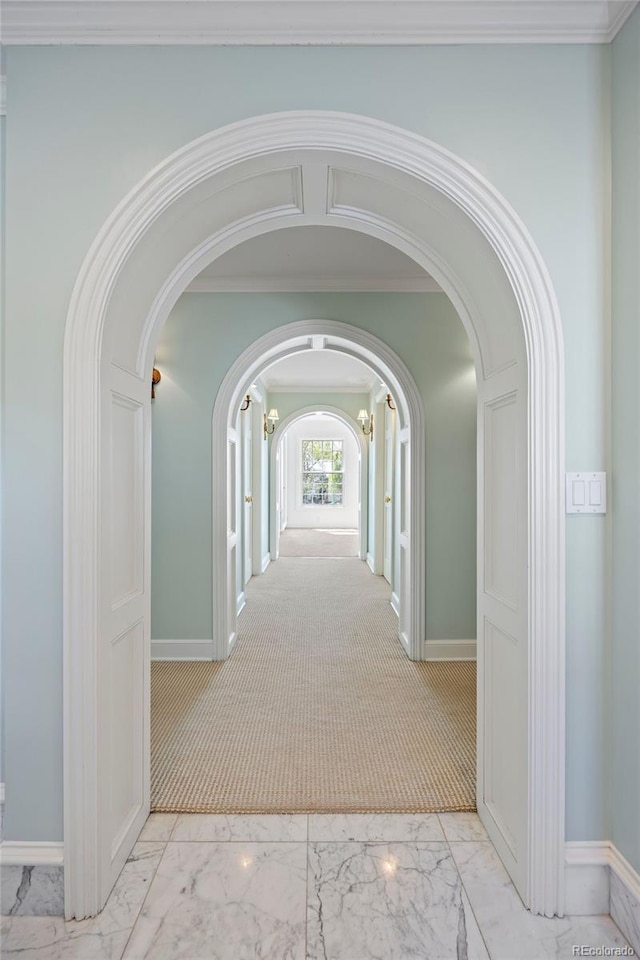 corridor with arched walkways, marble look tiles, and baseboards