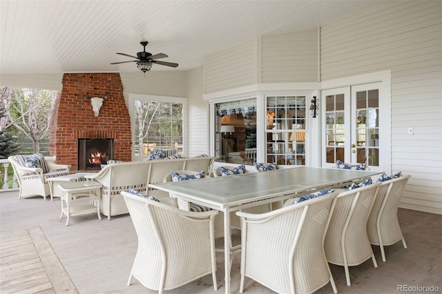 dining area with ceiling fan, healthy amount of natural light, an outdoor brick fireplace, vaulted ceiling, and wood walls