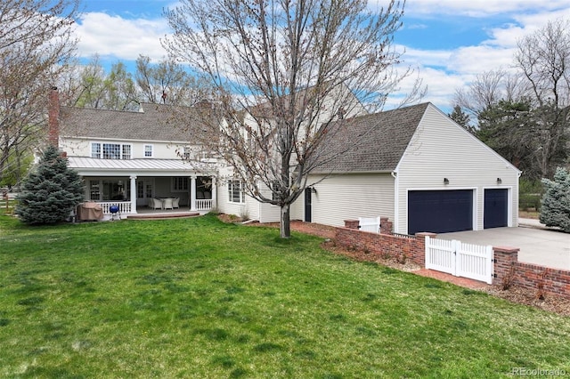back of property with concrete driveway, a gate, a chimney, an attached garage, and roof with shingles