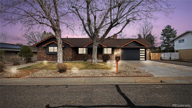 view of front facade with brick siding, fence, a chimney, a garage, and driveway