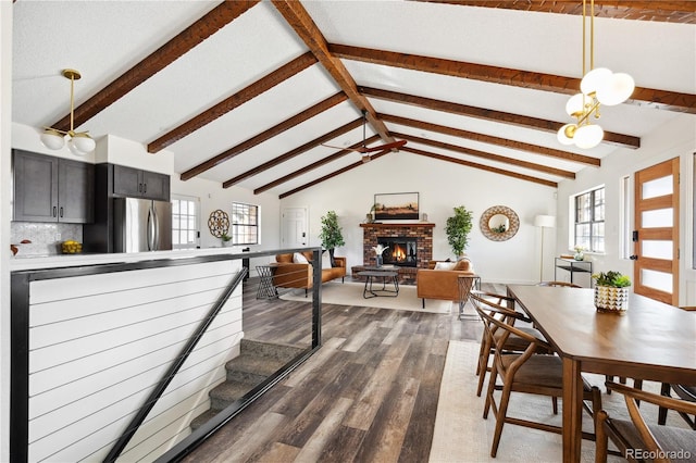 dining room with a brick fireplace, dark wood finished floors, and vaulted ceiling with beams