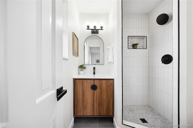 bathroom featuring tile patterned floors, vanity, and a tile shower