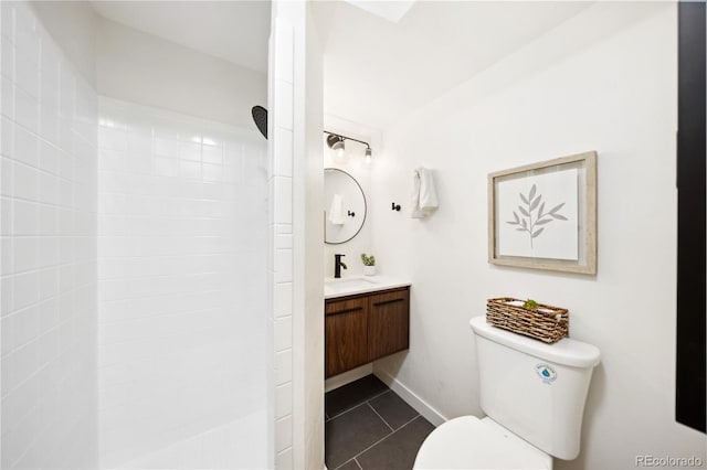 bathroom with vanity, baseboards, tiled shower, tile patterned flooring, and toilet