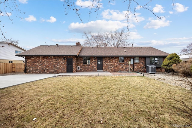 rear view of property featuring brick siding, fence, a lawn, cooling unit, and a chimney