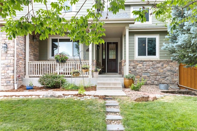 view of exterior entry with stone siding and a porch