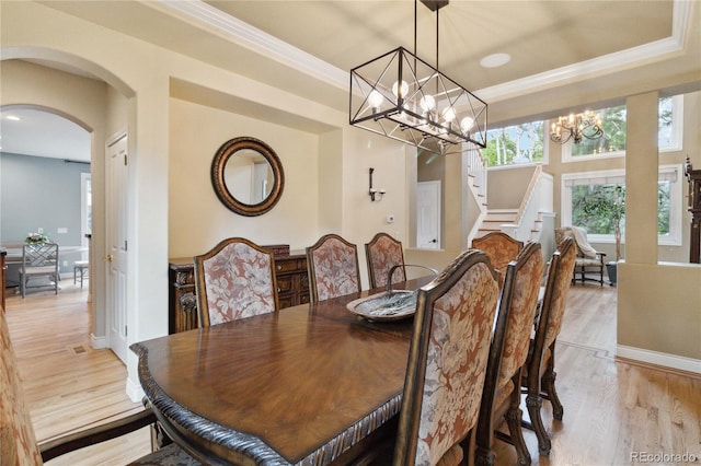 dining area with a chandelier, stairway, arched walkways, light wood-type flooring, and crown molding