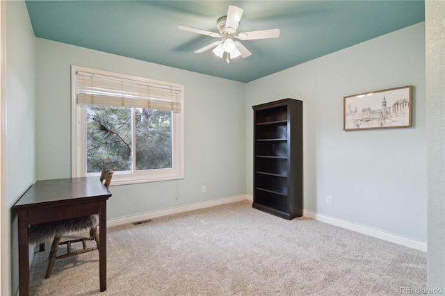carpeted office space featuring ceiling fan and baseboards