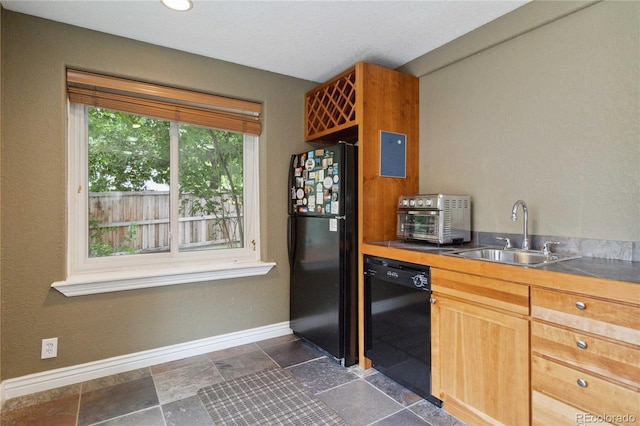 kitchen with black appliances, a sink, baseboards, and dark stone finish flooring
