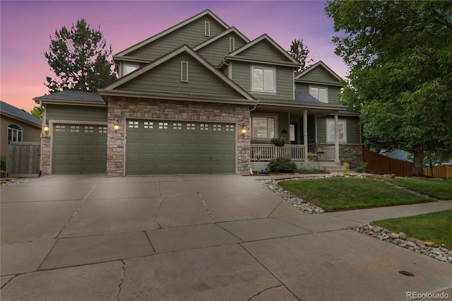 craftsman house with covered porch, a garage, concrete driveway, and stone siding