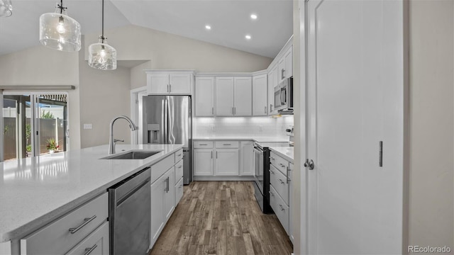 681 Eadin Ln, Grand Junction, CO 81504 - kitchen featuring appliances with stainless steel finishes, wood finished floors, white cabinetry, decorative backsplash, and hanging light fixtures
