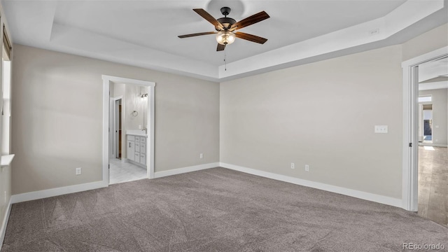 681 Eadin Ln, Grand Junction, CO 81504 - unfurnished bedroom with a tray ceiling, carpet flooring, connected bathroom, and ceiling fan