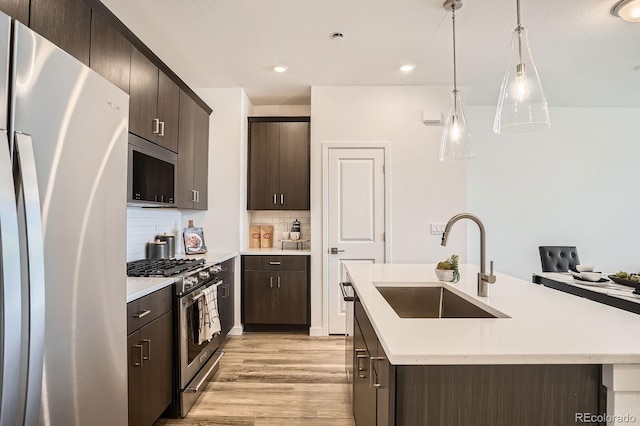 370 Geneva St, Aurora, CO 80010 - kitchen featuring stainless steel appliances, light wood-style floors, a kitchen island with sink, dark brown cabinets, and recessed lighting