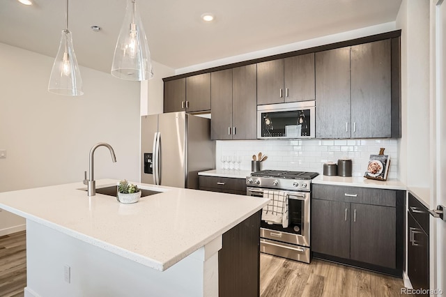 370 Geneva St, Aurora, CO 80010 - kitchen with stainless steel appliances, light wood finished floors, backsplash, an island with sink, and dark brown cabinetry