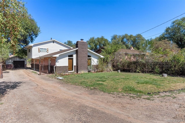 view of property exterior with an outbuilding, driveway, a chimney, a lawn, and brick siding