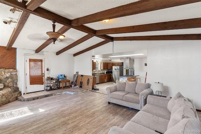 living area featuring light wood-style flooring, a textured ceiling, lofted ceiling with beams, and ceiling fan