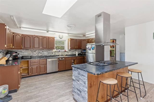 kitchen featuring stovetop, a kitchen breakfast bar, island exhaust hood, freestanding refrigerator, and stainless steel dishwasher