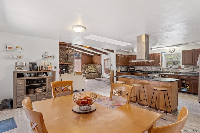 dining area with lofted ceiling with skylight and light wood-style floors